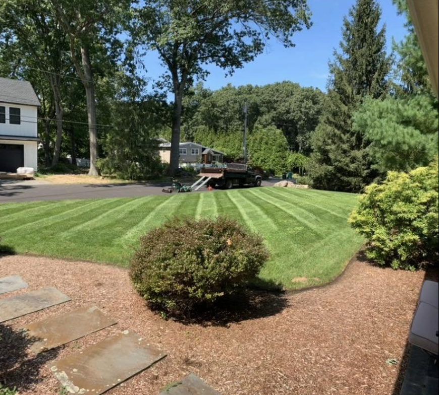 G&M Landscaping lawn with fresh mowing stripes and mulched garden beds
